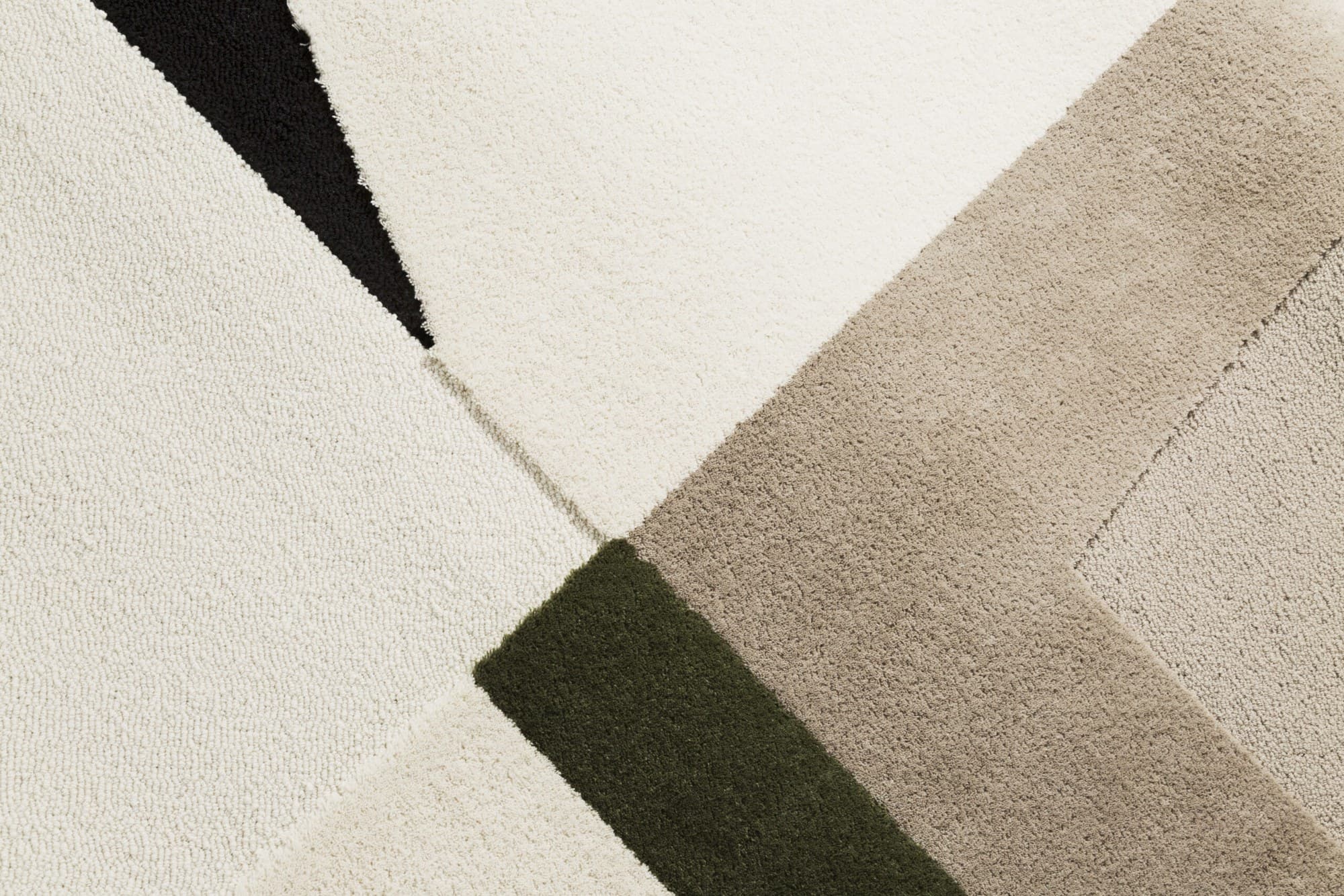 Detalle de una carpeta de lana: pelo cortado crema con una cuña verde oliva y un vértice negro