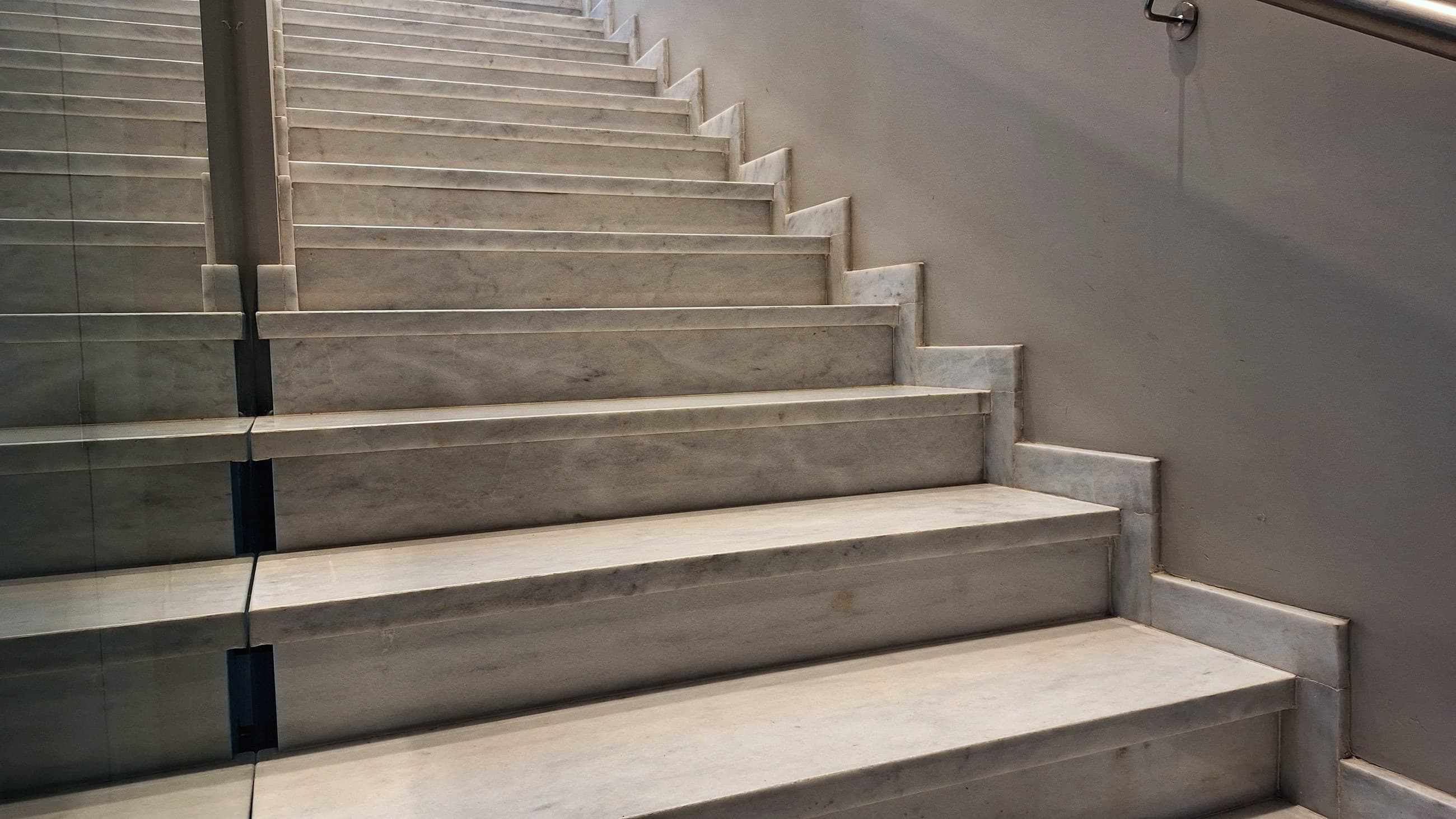 Escalera revestida en travertino con baranda de vidrio