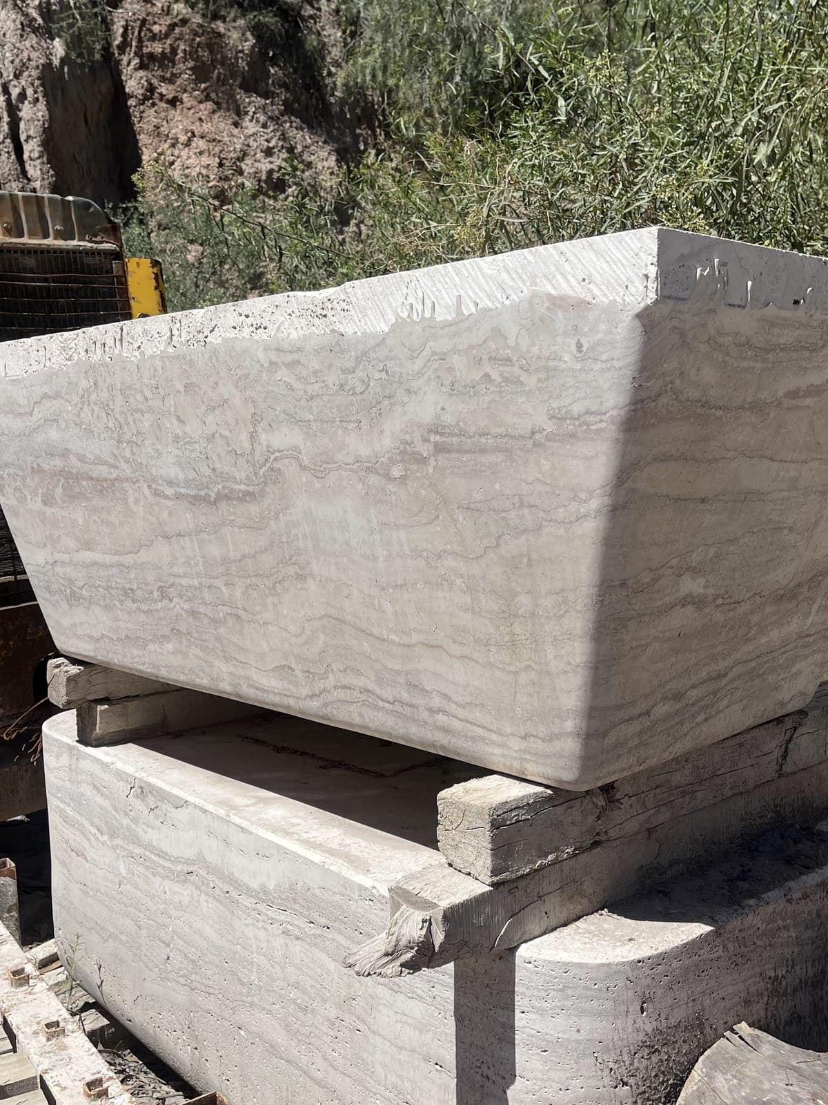 Pieza maciza de travertino nacional apoyada sobre pallets en el taller