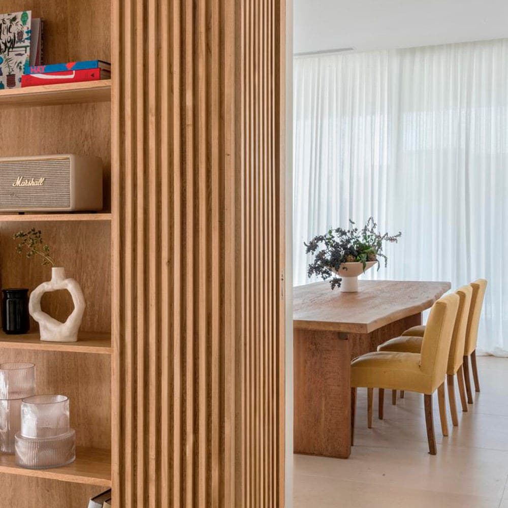 Comedor con piso de Caliza Saint Remy junto a un tabique de listones