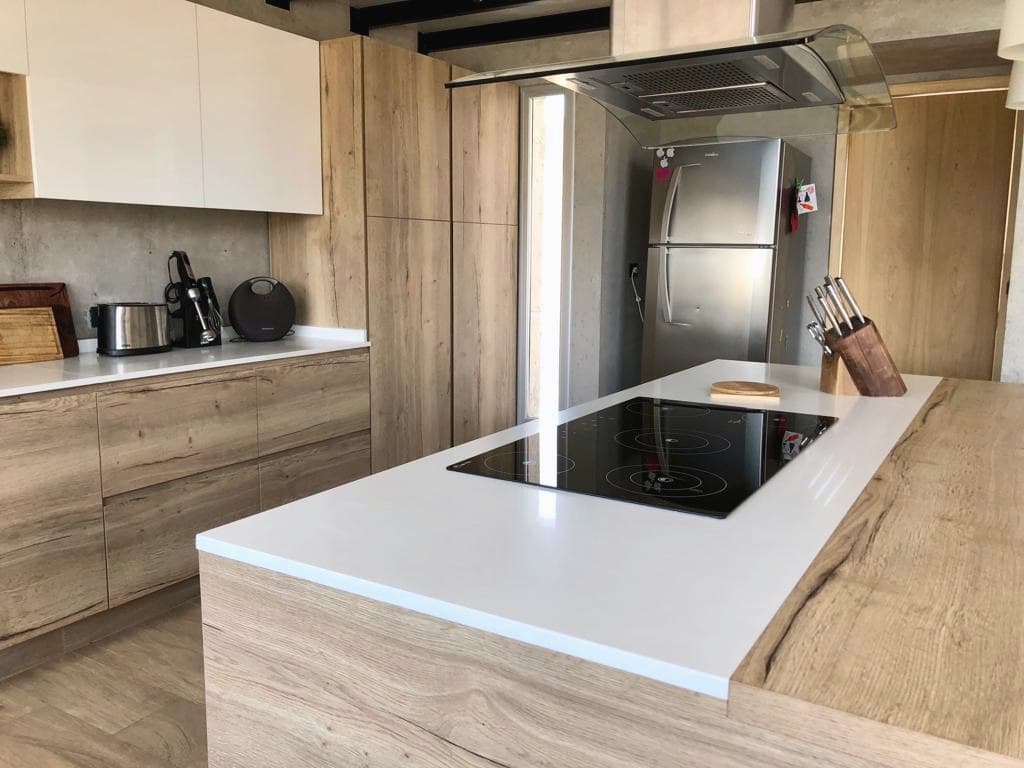 Mesada de cuarzo blanco sobre isla de madera, con anafe empotrado