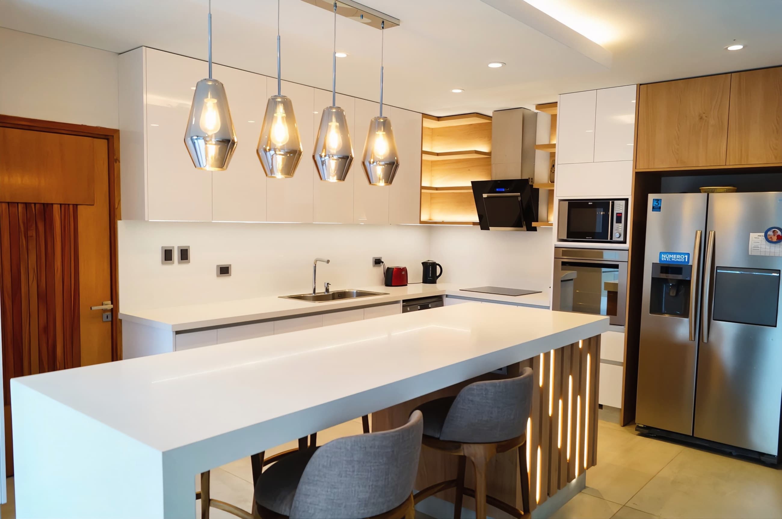 Isla de cocina con mesada de cuarzo blanco y colgantes de vidrio